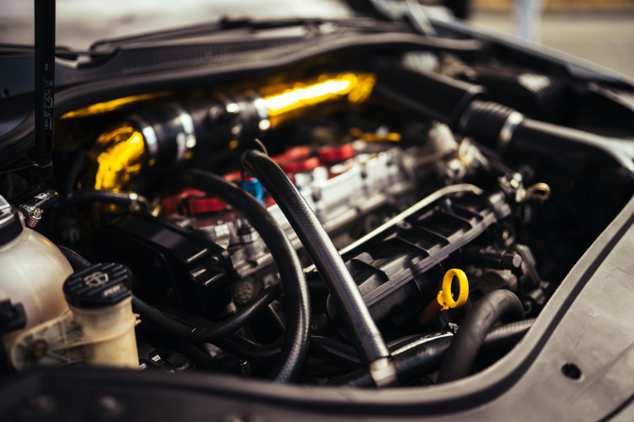 Used Engine Verification – 5 Key Steps Before Final Assembly Otwarta komora silnika samochodowego z rzucającym się w oczy żółtym bagnetem oleju oraz plątaniną przewodów, ilustrująca proces weryfikacji technicznej jednostki napędowej.